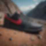 Sleek black leather Nike shoe with red accents on a gravelly slope