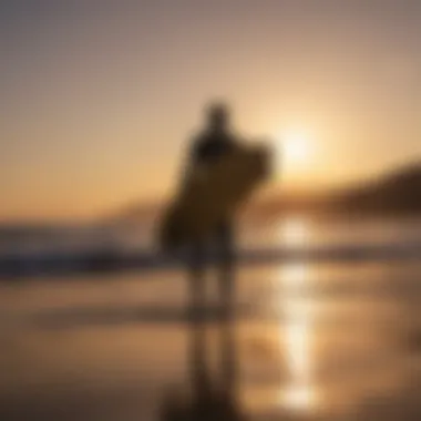 Sunset silhouette of a surfer carrying a 7ft surfboard